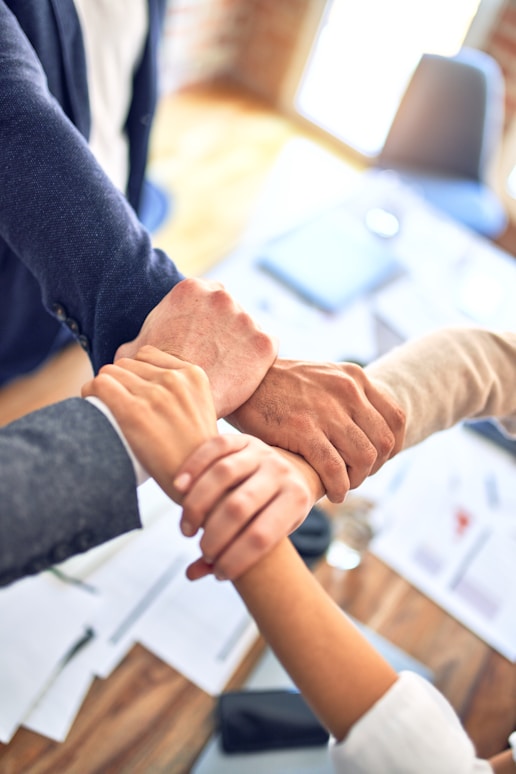 Photo of four hands holding each other's wrists to symbolize collaboration.